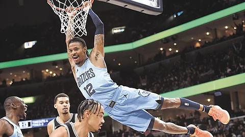 Memphis Grizzlies guard Ja Morant (12) hangs from the rim after dunking against the San Antonio Spurs in the second half of an NBA basketball game Tuesday, Jan. 2, 2024, in Memphis, Tennessee.