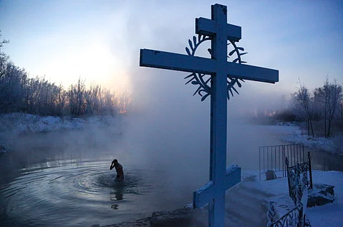 A man crosses himself while bathing in the water during a traditional Epiphany celebration as the temperature dropped to about -24 degrees (-11,2 degrees Fahrenheit) near the Achairsky monastery outside Siberian city of Omsk, Russia, Tuesday, Jan. 19, 2021. Water that is blessed by a cleric on Epiphany is considered holy and pure until next year's celebration, and is believed to have special powers of protection and healing. The Russian Orthodox Church follows the old Julian calendar.