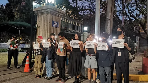 MANILA. Members of the progressive group Anakbayan hold a prayer vigil outside the University of Santo Tomas in Manila in protest on February 24, 2024, against the "attacks on press and academic freedom" allegedly ordered by the UST Office of Student Affairs towards its campus media organization, TomasinoWeb.