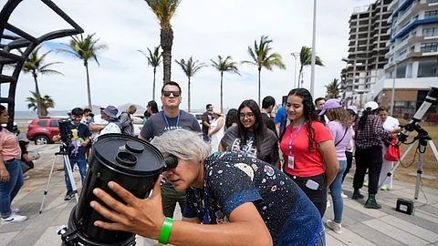 An amateur astronomer prepares her telescope a day before a total solar eclipse in Mazatlan, Mexico, on Sunday, April 7, 2024.