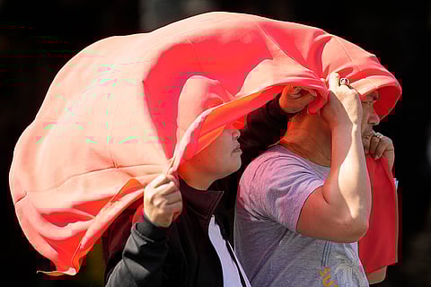 A man and woman use a cloth over their heads to protect themselves from the sun in Manila, Philippines on April 29, 2024. In a world growing increasingly accustomed to wild weather swings, the last few days and weeks have seemingly taken those environmental extremes to a new level.
