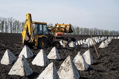 Workers install anti-tank systems known as “dragon teeth” during construction new defensive positions close to the Russian border in Kharkiv region, Ukraine, on Wednesday, April 17, 2024.