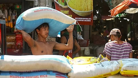 A laborer carries a sack of rice to his employer’s store, as more sacks of rice are waiting to be transferred and arranged in a stall at a public market in Davao City. The RTWPB-Davao approved an increase of P38 per day to the minimum wage workers in the region to be given in two tranches, the first tranche of which amount to P19 per day took effect on March 6, 2024.