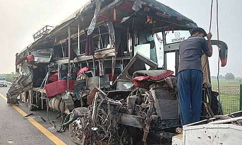 A roadside assistance worker tows away the mangled remains of a double-decker passenger bus that collided with a milk truck, near Unnao, in northern India state of Uttar Pradesh, Wednesday, July 10, 2024. Officials said the collision killed and injured multiple people.