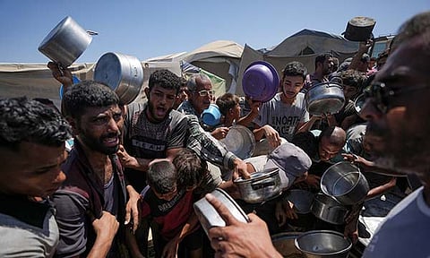 Displaced Palestinians gather at a food distribution center in Deir al Balah, central Gaza Strip, Friday, Aug. 23, 2024.