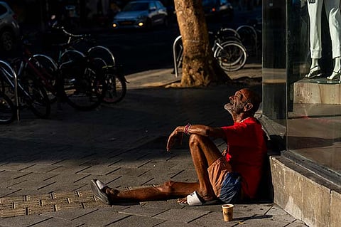 A person sits on the sidewalk next to a mall in Tel Aviv, Israel, Thursday, Aug. 15, 2024. Israel's economy is suffering from the nearly 11-month war with Hamas, as its leaders grind ahead with its offensive in Gaza that threatens to escalate into a wider conflict.