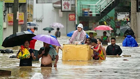 MANILA. Residents along a flooded street caused by heavy rains from Tropical Storm Yagi, locally called Enteng, on Monday, September 2, 2024, in Cainta, Rizal province, Philippines.
