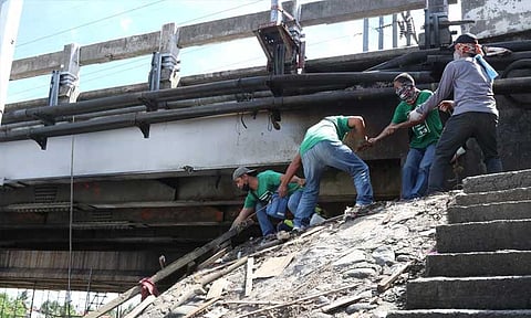 HELPING HAND. Personnel of the City Government of Davao help each other to pull the large piece of wood from the fire site under the Bolton Bridge along Quimpo Boulevard, Davao City. The Bureau of Fire Protection (BFP) reported around P200,000 worth of damage due to the fire incident on January 15, 2022.