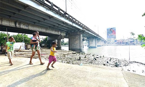 A woman and children walk past the Bolton Bridge in Davao City.