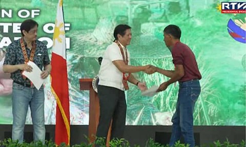 DEBT CONDONATION. President Ferdinand R. Marcos Jr. leads the distribution of Certificates of Condonation and Release of Mortgage to 3,527 agrarian reform beneficiaries (ARBs) in a ceremony at the Eduardo Cojuangco Gymnasium in Paniqui, Tarlac on Monday (Sept. 30, 2024). The condonation of all unpaid principal amortizations, interest, and surcharges of ARBs on agricultural lands awarded under the agrarian reform program is mandated under Republic Act 11953 or the New Agrarian Emancipation Act (NAEA), which the President signed into law in July 2023. (RTVM Screengrab)