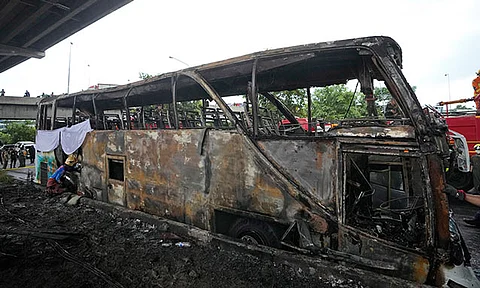 A rescuer inspects a bus that caught fire, carrying young students with their teachers, in suburban Bangkok, Tuesday, Oct. 1, 2024.
