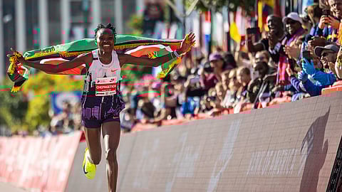 Ruth Chepngetich, from Kenya, runs with the Kenyan flag after crossing the finish line of the Chicago Marathon to win the women's professional division and break the women's marathon world record in Grant Park, Sunday, October 13, 2024. (AP)