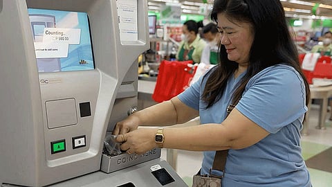 Sari-sari store owner Vilma Guray deposits her coins in the Coin Deposit Machine. (Photo courtesy of BSP)