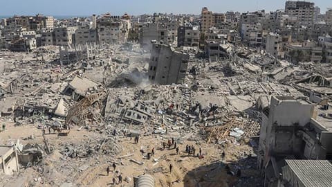 Palestinians walk through the destruction left by the Israeli air and ground offensive on the Gaza Strip near Shifa Hospital in Gaza City, on April 1, 2024.