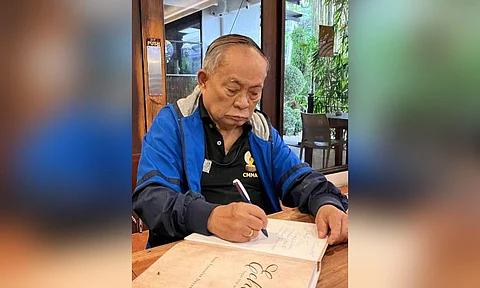 AKLAN. Johnny Dayang, known as one of the oldest Filipino surviving journalists, signs his first book “Echoes from the Woodwork,” a collection of his newspaper columns, for a friend in January 2025.