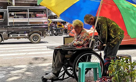 LOVE EVERLASTING. A man inflates the tires of his wife's wheelchair while he parked it under under the shade of a tree at Osmeña Park Tuesday morning along A. Pichon Street in Davao City.