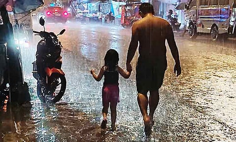 BAREFOOT IN THE RAIN. In this file photo, a man and his young daughter walk barefoot through a sudden downpour in Davao City on July 25. Walking barefoot on wet streets poses risks, such as slippery roads and sharp debris. It could also cause them to acquire infectious diseases like leptospirosis and even get parasites. Still, the two pressed on, sharing a quiet, tender moment under the rain