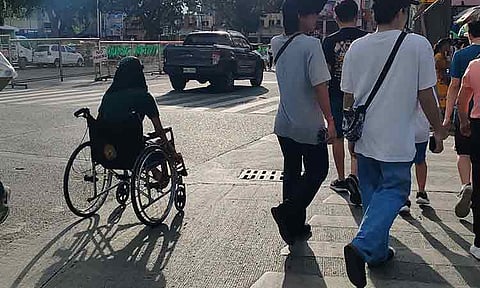 A wheelchair user crosses the pedestrian lane along San Pedro Street in Davao City.