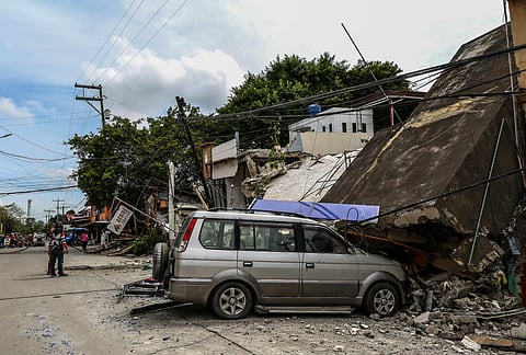 Debris from collapsed structures blocks a portion of a road in northern Cebu after the magnitude 6.9 earthquake, leaving parts of the area impassable to vehicles.