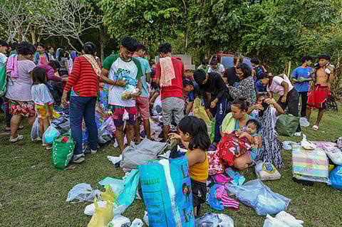 RUMMAGE FOR RELIEF. Residents of Barangay Binabag in Bogo City rush to pick up donated clothing on October 2, 2025, days after Cebu was devastated by a 6.9-magnitude earthquake.