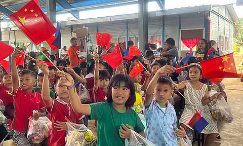 FLAGS OF HOPE. Magbok Fil-Chinese Friendship School students wave small Philippine and Chinese flags while holding snack and gift bags from the Association of Davao Fil-Chinese Communities and the Chinese Consulate General in Davao during the school’s formal turnover ceremony on Dec. 19, 2025.