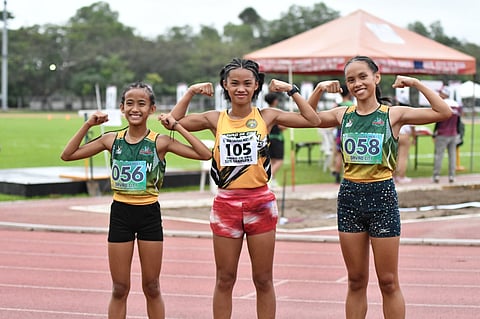 TOP THREE STRONG. Davao de Oro’s Charlene Cos, center, celebrates her gold medal victory with a flex and a smile, flanked by fellow medalists Rhianne Mae Mañacap (bronze) and Faith Marie Ocon (silver) of Davao City, after the secondary girls’ 3,000-meter run at the 2026 Davao Region Athletic Association (Davraa) Meet at the Davao del Norte Sports and Tourism Complex in Tagum City Monday, February 23. Cos also claimed the meet’s first championship title.