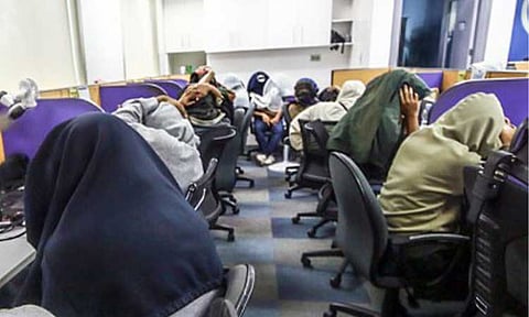 RAIDED. Employees of a Pasig City firm operating an online lending app cover their faces during a government raid on July 15, 2025. The Philippine National Police on Tuesday (March 17, 2026) said it is intensifying efforts against abusive lending platforms involved in harassment, privacy violations and cybercrime offenses. (PNA photo by Joan Bondoc)