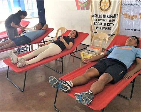 Club president Trixie Villavicencio joins police officers in donating blood. (Contributed photo)