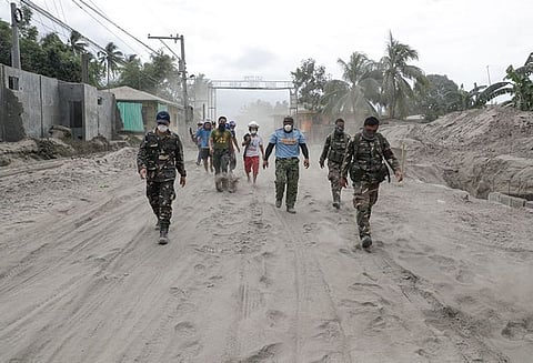 BATANGAS. Police and military men walk along a road covered in volcanic ash at a village beside Taal volcano where residents have evacuated to safer ground in Agoncillo, Batangas province on Saturday, January 18, 2020. (AP)