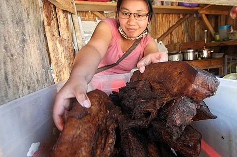 MOUNTAIN PROVINCE. A vendor in Sagada, Mountain Province checks on the quality of etag, a preserved pork meat, sold at the town's market for P270 per kilo. (Jean Nicole Cortes)