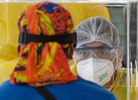 MANILA. A health worker ask questions of visitors as they conduct mass testing for Covid-19 in Manila, Philippines on Friday, May 8, 2020. (AP)
