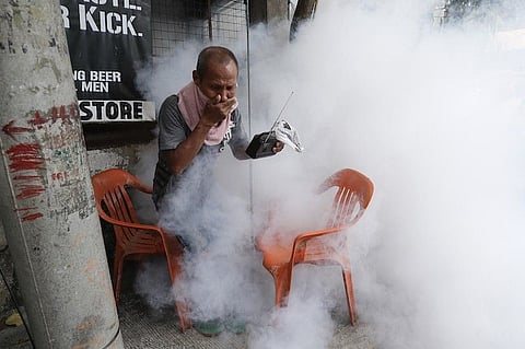 MANILA. In this photo taken on March 15, 2021, a resident holds his nose and portable radio as he tries to avoid the disinfectants used on their village as a precaution against the spread of Covid-19 in Manila. (File)