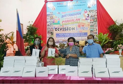 BACOLOD. Bacolod City Division Superintendent Gladys Amylaine Sales, CESO VI (2nd from left), turns over tablet units to Alangilan National High School OIC-Principal Veneranda (2nd from right) during the Brigada Eskwela 2021 opening rites at the Social Hall of the Bacolod City Division. Also in the photo are CID chief Dr. Janalyn Navarro and Assistant Superintendent Peter Galimba. (Jerome Galunan Jr.)