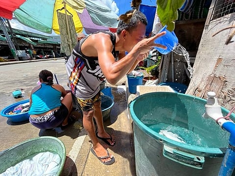 CEBU. A resident of Sitio Katsilaan, Barangay Ermita, Cebu City is pouring water on his face as he takes a bath while a woman is washing the laundry Thursday, July 14, 2022. The MCWD says Thursday that it lacks water supply to accommodate the needs of it consumers. (Amper Campaña)