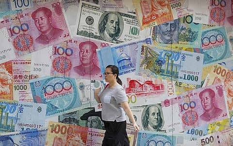 A woman walks by a money exchange shop decorated with different countries currency banknotes at Central, a business district in Hong Kong, Tuesday, Aug. 6, 2019. As the value of the U.S. dollar soars, other currencies around the world are sinking by comparison. (AP Photo/Kin Cheung, File)