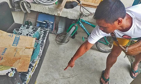 SEE THE CRACK. A man points at the crack on the floor of his house in Barangay Candulawan, Talisay City. The crack appeared after the alleged treasure hunting activity in the area. / CONTRIBUTED
