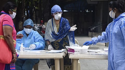 Health workers talk with a resident during a medical screening for the COVID-19.