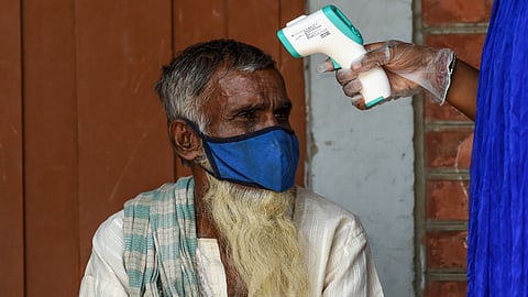 A 'Covid-19 Awareness Project' volunteer measures the body temperature