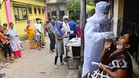A health worker wearing protective gear collects a swab sample