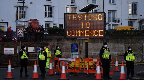 Police officers stand on duty at beneath a sign reading "Testing to Commence