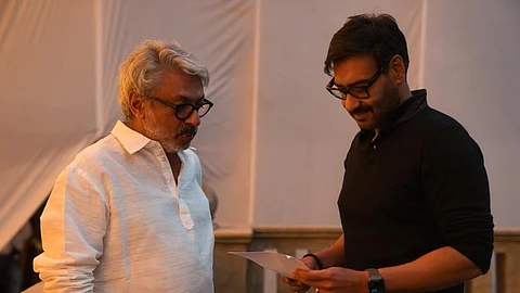 In the image, Ajay Devgn is reading the script and Sanjay Leela Bhansali is seen standing next to him on the sets of Gangubai Kathiawadi.