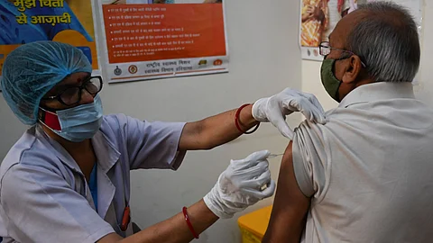 A health worker (L) inoculates a senior citizen with a Covid-19 coronavirus vaccine at a government hospital in Faridabad
