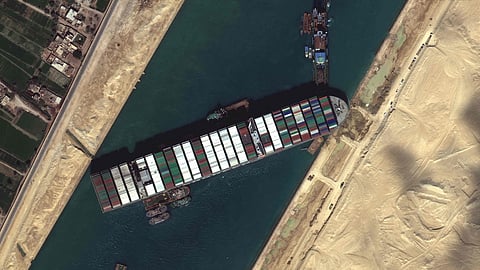 This satellite imagery released by Maxar Technologies shows tug boats and dredgers on March 27, 2021, attempting to free the Taiwan-owned MV Ever Given lodged sideways and impeding all traffic across Egypt's Suez Canal. - The container ship, which is longer than four football fields, has been wedged diagonally across the entire canal since March 23, shutting the waterway in both directions.