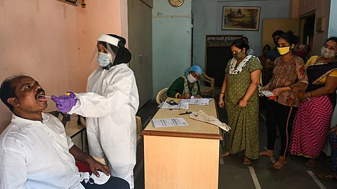 A health worker takes a swab sample from a youth as mandated by civic authorities to undergo a COVID-19 Test inside Dharavi slums, in Mumbai