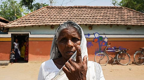 A voter shows her inked finger after casting her vote, outside a polling station during Phase 1 of West Bengal's legislative election in Purulia district on March 27, 2021.