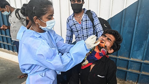 A health worker takes a swab sample of a passenger for a Rapid Antigen Test (RAT) at a railway station during weekend lockdown restrictions imposed by the state government amidst rising COVID-19 cases, in Mumbai