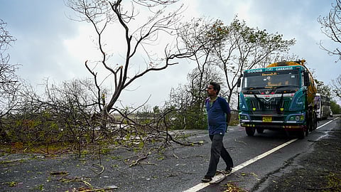 A man walks past stranded trucks at a highway near Diu on Tuesday after Cyclone Tauktae hit the west coast of India