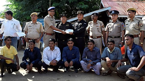 Seven Rohingya men to be deported sit as Indian and Myanmar security officials exchange documents before their deportation on India-Myanmar border at Moreh in the northeastern state of Manipur, India, on October 4 | Photo credit: Reuters