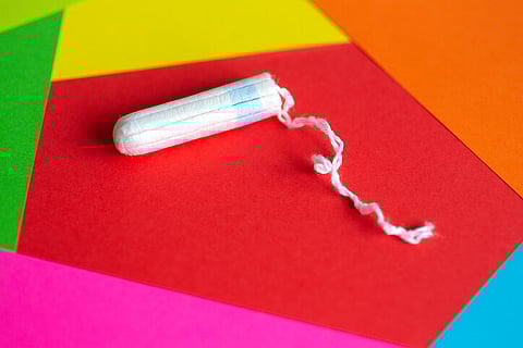 Feminine hygiene tampon on red, pink, orange background, close up