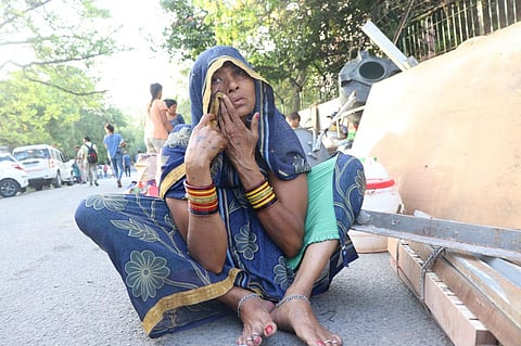 पीजी कैम्पः मकान टूटने के बाद सड़क पर उदास बैठी महिला।